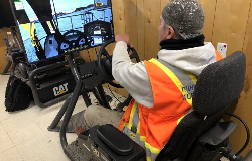 A Ledcor employee safely practices operating a mining truck on a Cat Simulator mining truck system.